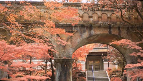 Puente-De-Ladrillo-Rodeado-De-Hojas-Naranjas-De-Otoño-En-Kyoto,-Japón-Plano-General-4k