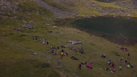 Círculo-Aéreo-Alrededor-De-Un-Gran-Grupo-De-Personas-Que-Se-Relajan-En-Un-Lago-De-Montaña,-Montañas-Rodnei,-Rumania