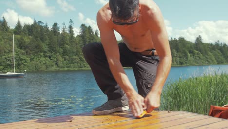 Topless-young-carpenter-working-on-wooden-boat-roof