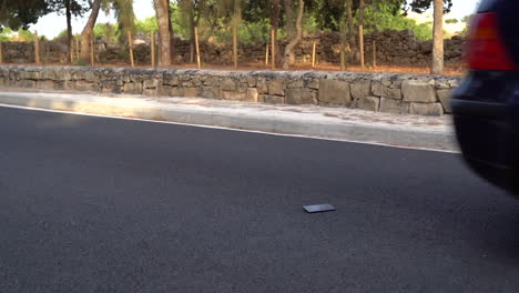 Car-tires-driving-over-mobile-smart-phone-gorilla-glass-on-normal-road-with-tarmac---wide-angle