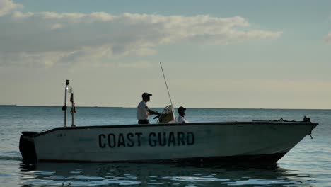 Ein-Schnellboot-Der-Küstenwache-Mit-Zwei-Männern-Darin,-Das-Sich-Nach-Rechts-In-Ufernähe-Bewegt