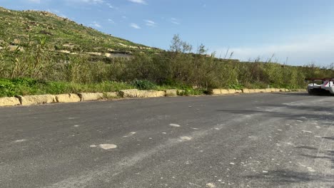Racing-Car-Passing-By-The-Road-Track-At-The-Lush-Hil-In-Imtahleb-Malta-On-A-Hot-Sunny-Weather---Closeup-Shot
