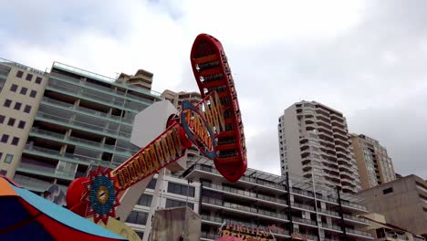 Luna-Amusement-Park-with-Ranger-spinning-boat-ride-in-motion,-northern-shore-on-a-cloudy-day,-Handheld-tracking-shot