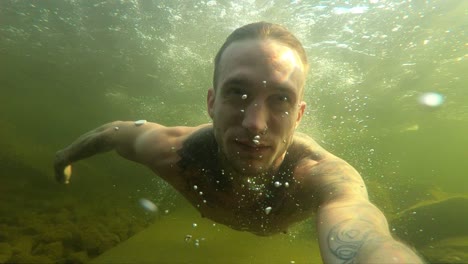 A-young-man-films-himself-with-an-action-camera-as-he-swims-through-the-dark,-gloomy-and-murky-the-cold-Norwegian-water-during-a-hot-summer-day