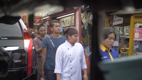 A-big-line-of-locals-waiting-on-the-sidewalk-to-board-the-bus-at-a-bus-stop-in-Jakarta,-Indonesia-during-sunset