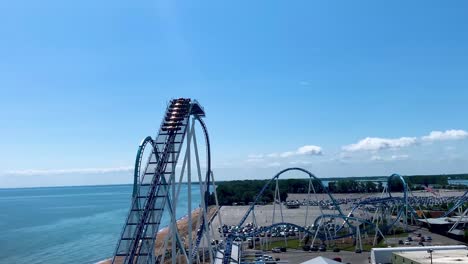 4K-Aerial-video-of-Gatekeeper-roller-coaster-with-cloudy-blue-sky-background-at-cedar-point-amusement-park-in-Sandusky,-Ohio,USA