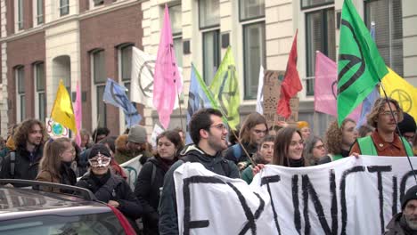 Demonstranten-Der-Extinction-Rebellion-Marschieren-In-Amsterdam-Mit-Demonstranten,-Die-Schilder-Und-Fahnen-Halten