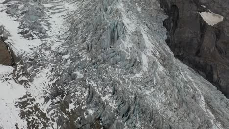 Drone-shot-panning-up,-showing-sharp-edges-and-lines-of-the-epic-and-big-glacier-with-its-unique-and-strong-patterns-and-lines