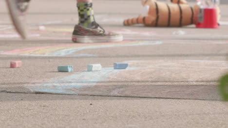 Youthful-boy's-hand-grinding-chalk-onto-city-sidewalk,-Close-Up,-Slow-Motion