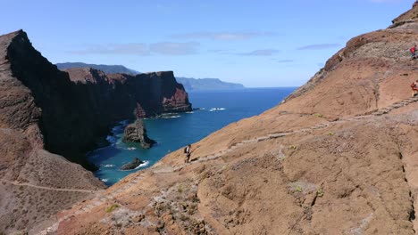 AERIAL:-Person-exploring-cliffs-by-the-ocean-in-Madeira-Portugal