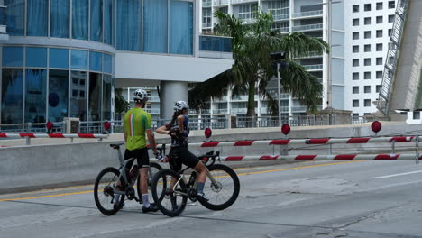 Radfahrerpaar-Wartet-Während-Des-Covid-19-Ausbruchs-Auf-Geschlossener-Rampe-Vor-Der-Zugbrücke-In-Der-Innenstadt-Von-Miami,-Florida,-USA,-50-Fps