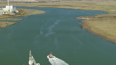 Aerial-tracking-shot-of-a-RNLI-Lifeboat-crew-sailing-down-the-Swale-Estuary-between-Ridham-Dock-at-Kemsely-and-the-Isle-Of-Sheppey
