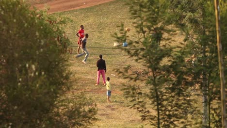Blick-Zwischen-Grünen-Bäumen-Auf-Afrikanische-Kinder,-Die-An-Einem-Sonnigen-Tag-Auf-Grünem-Rasen-Fußball-Spielen,-Lushoto,-Tansania,-Statisch
