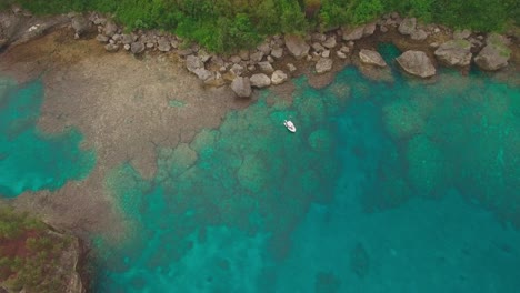 Aerial-View-of-Lonely-Boat-in-Turquoise-Water-by-Rocky-Coast-of-Exotic-Island