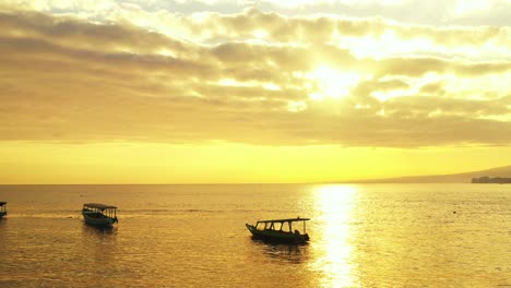 Fishing-boats-in-the-calm-tropical-sea-on-the-early-morning,-golden-sunrays-showing-under-the-dramatic-clouds