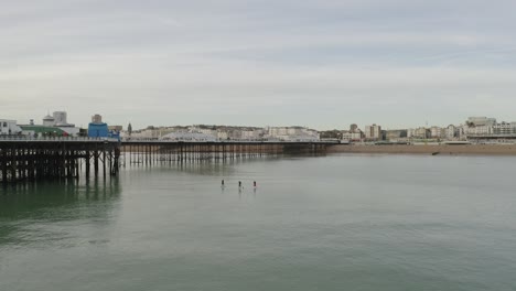 People-on-paddle-boards-near-Brighton-pier-with-seagulls-flying-past-and-beach-in-view