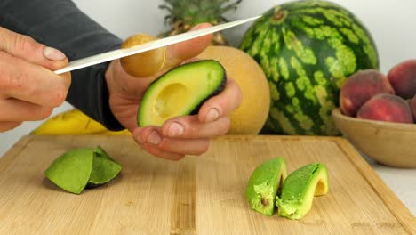 Force-is-used-with-a-knife-to-hack-into-an-avocado-core-to-loosen-it-from-the-creamy-flesh