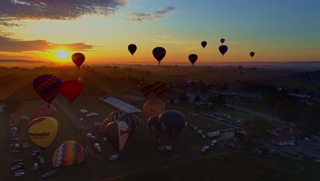 Vista-Aérea-De-Un-Lanzamiento-Matutino-De-Globos-Aerostáticos-En-Un-Festival-De-Globos-Desde-El-Llenado-Hasta-El-Despegue-Visto-Por-Un-Dron