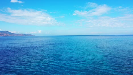 Wunderschöne-Kristallklare,-Türkisfarbene-Meerwasserinsel-Und-Berge,-Die-Im-Hintergrund-Von-Weißen,-Flauschigen-Wolken-Bedeckt-Sind