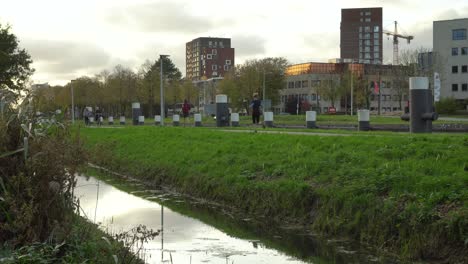 Cyclists-and-runners-on-cycling-path-beside-canal,-Netherlands,-still-shot