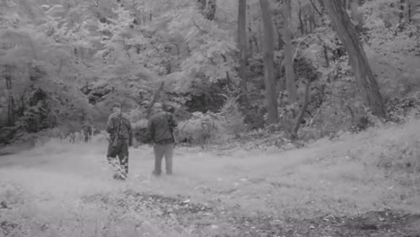 Two-hunters-casually-walking-along-a-game-trail-in-the-woods