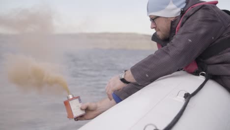 A-Seaman-Uses-Buoyant-Smoke-Signal-In-Distress-Signal-Testing-During-Nautical-Training-In-Patagonian-Sea---Closeup-Shot