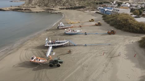 Menschen-An-Der-Küste-Des-Patagonischen-Meeres-In-Der-Nähe-Von-Booten,-Die-An-Einem-Sonnigen-Tag-An-Schwere-Traktoren-Gezogen-Wurden---Luftaufnahme
