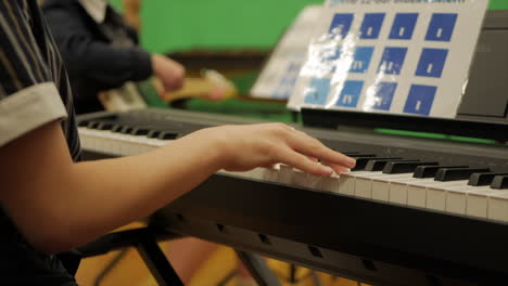 Junges-Mädchen-Spielt-E-Piano-Bei-Der-Probe-Einer-Schulband,-Nahaufnahme
