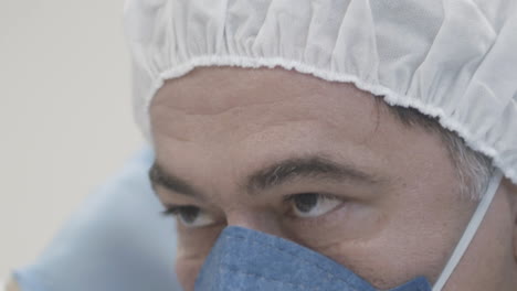 Extreme-close-up-shot-of-doctor-wearing-face-mask-putting-on-a-surgical-cap