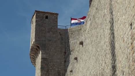 Vista-De-La-Bandera-Croata-Ondeando-En-La-Parte-Superior-De-Una-Torre-De-Vigilancia-A-Lo-Largo-De-La-Pared-En-El-Casco-Antiguo-De-Durbrovnik,-Croacia