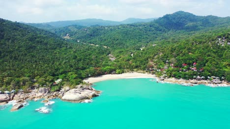 Beautiful-tropical-island-with-green-hills-full-of-rainforest,-secret-white-sandy-beach-and-cliffs-on-shore-washed-by-turquoise-lagoon,-Thailand