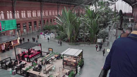 Gente-Caminando-Por-La-Plaza-Interior-De-La-Antigua-Estación-De-Tren-De-Atocha-En-Madrid,-España