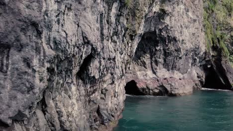 Secret-Hidden-beach-with-natural-volcanic-limestone-sea-caves-black-sand-and-crystal-clear-turquoise-water---4K-dolly-Shot