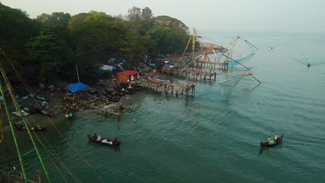 Fishing-net,-traditional-cultural-job-occupation-of-fish-business-in-Kerala-India-seashore-fish-market-and-wooden-boats-teamwork-in-tropical-aerial-view