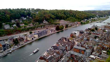 Boat-sailing-through-city-centre-of-Dinant,-Belgium-on-river-Maas