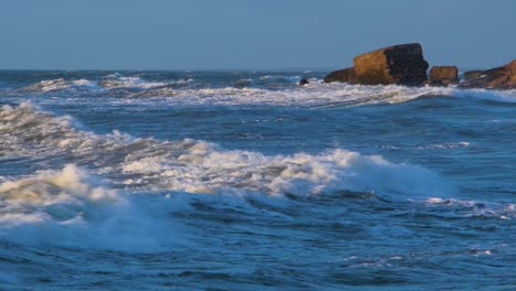 Man-engaged-in-kitesurfing-in-sunny-autumn-day,-high-waves,-Baltic-Sea-Karosta-beach-in-Liepaja,-medium-shot