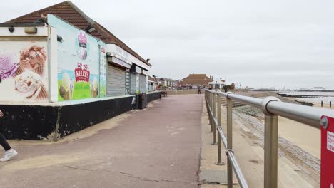 Two-young-girls-walking-along-sea-front-in-English-seaside-town