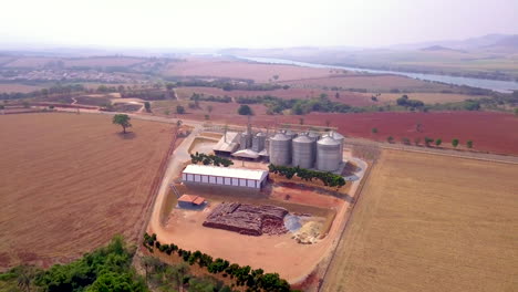 Grain-storage-silos-on-agricultural-land,-wide-angle-orbiting-aerial-shot