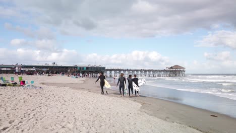 Slow-Motion,-Surfers-Walk-by-Ocean-Waves-on-Famous-Cocoa-Beach,-Florida