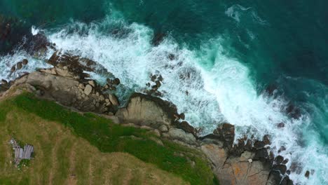 Top-down-view-of-big-waves-hitting-rocks