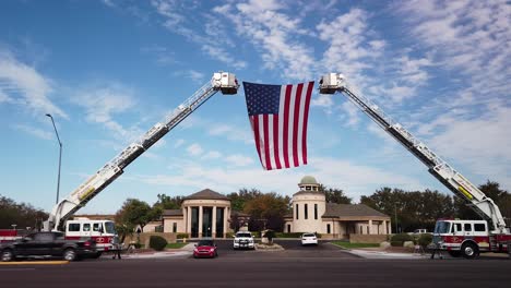 Als-Hommage-An-Einen-Gefallenen-Helden-Hängt-Eine-Riesige-Amerikanische-Flagge-Zwischen-Zwei-Feuerwehrautoleitern