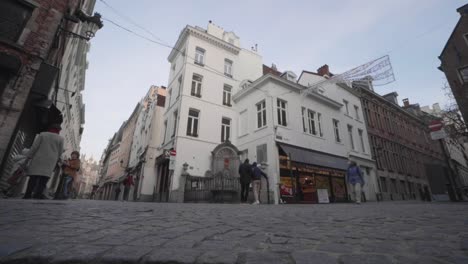 Personas-Con-Mascarilla-Obligatoria-Pasando-Por-La-Famosa-Atracción-Turística-Manneken-Pis-En-Bruselas,-Bélgica