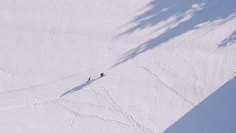 Drone-flight-with-to-skiing-people-at-a-snowy-white-winter-track,-filmed-straight-from-above,-couple-sports-at-the-cross-country-track