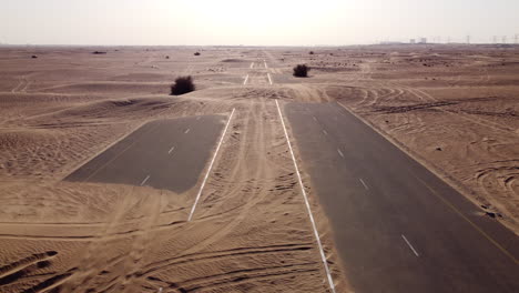 Aerial-flying-over-deserted-road-with-sand-on-asphalt-on-sunny-day