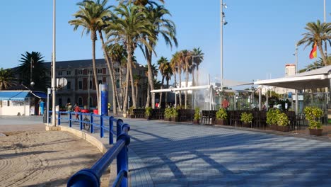 Locked-shot-of-People-with-mask-walking-along-the-beach-in-Alicante,-Spain