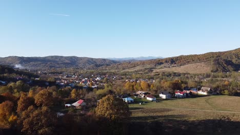 Luftaufnahme-über-Dem-Epischen-Bunten-Herbstwald-Und-Einem-Ländlichen-Dorf-An-Einem-Sonnigen-Tag