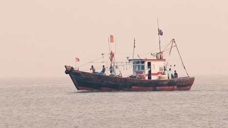 Ein-Kleines-Fischerboot,-Das-Mitten-Im-Meer-Segelt,-Mit-Einem-Fischer,-Der-Sich-Bei-Sonnenuntergang-Mit-Kleinen,-Ruhigen-Wellen-Auf-Das-Anlegen-Vorbereitet-Und-Bei-Nebligem-Wetter-Nach-Hause-Zurückkehrt.-Videohintergrund-In-Mov-In-Full-HD