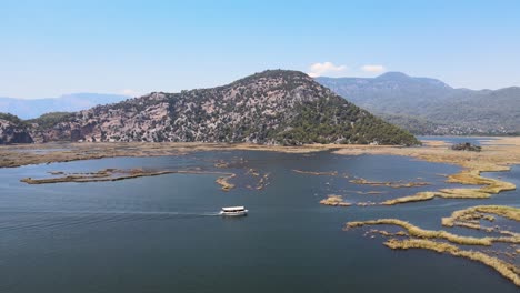 Filming-from-a-drone-of-a-pleasure-boat-against-the-background-of-a-green-mountain-frame-in-Turkey,-the-city-of-Dalyan-Turtle-Coast-Iztuzu