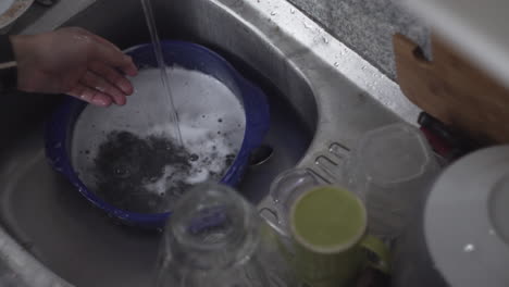 Washing-Dishware-Under-Running-Tap-Water-From-The-Faucet-Of-Kitchen-Sink