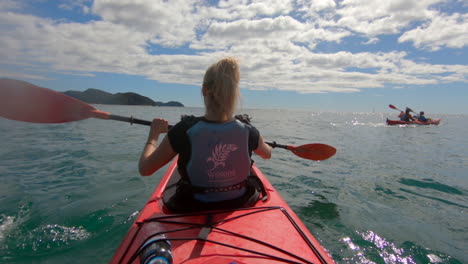 Schöne-Blonde-Frau-In-Einem-Roten-Kanu-Paddelt-über-Den-Ozean-Im-Abel-Tasman-Nationalpark-In-Neuseeland